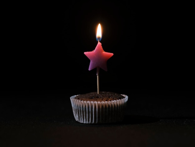 Una vela de cumpleaños encendida en un pastel de chocolate