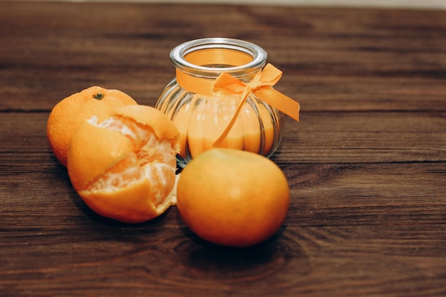 Vela de cera e laranja aromática em um castiçal sobre uma mesa de madeira