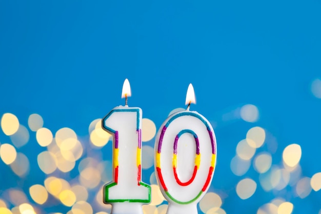Vela de comemoração de aniversário número 10 contra luzes brilhantes e fundo azul