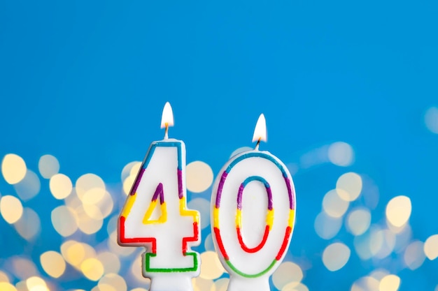 Vela de comemoração de aniversário número 40 contra luzes brilhantes e fundo azul