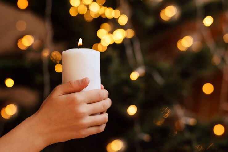 Foto vela de natal nas mãos das crianças no fundo de uma árvore de natal com guirlandas claras