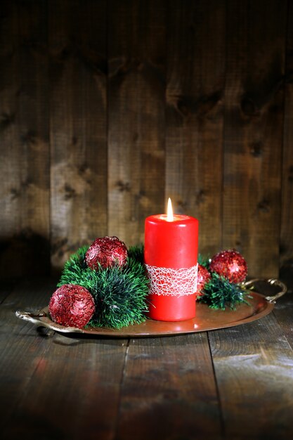 Vela encendida y adornos navideños sobre fondo de madera