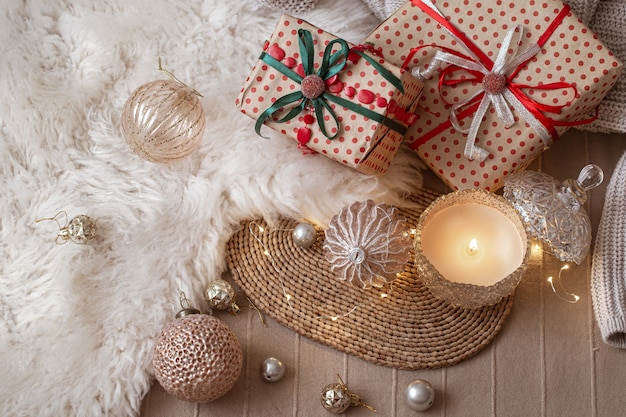 Vela encendida decorativa en el fondo de los regalos de Navidad con cosas acogedoras y detalles de decoración de cerca.