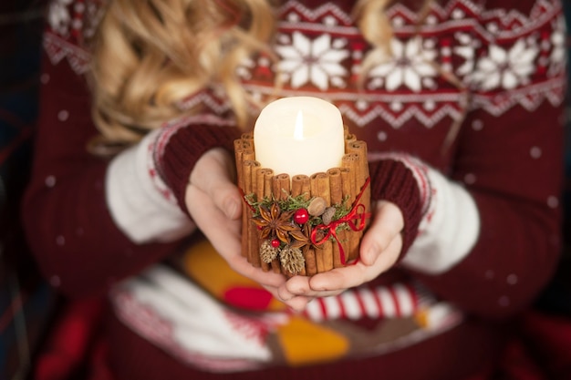 Vela encendida en manos de una niña. Vela navideña. Decoración navideña. Manos del niño sosteniendo hermosa vela con fuego