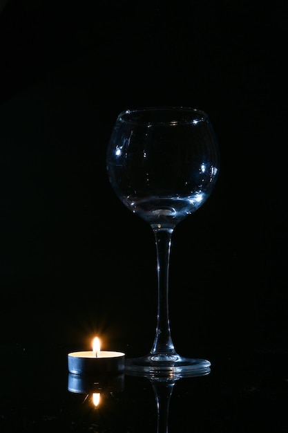 Foto vela encendida y vaso vacío sobre fondo oscuro