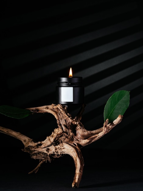 La vela se encuentra sobre una composición de fondo negro de raíces de árbol con reflejos