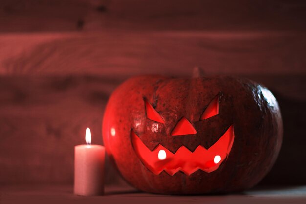 Vela y una espeluznante calabaza de Halloween sonriente sobre una mesa de madera.Foto con espacio de copia