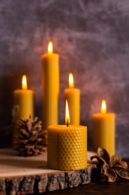 Una vela hecha a mano de cera natural con textura de panal de abejas arde sobre la mesa, un elemento inusual del interior.