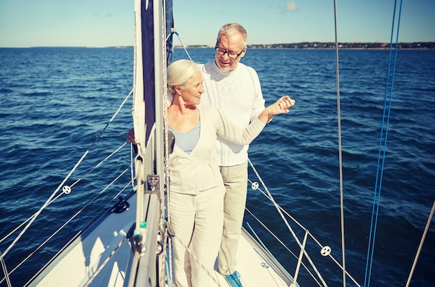 vela, idade, turismo, viagens e conceito de pessoas - feliz casal sênior abraçando no barco a vela ou no convés do iate flutuando no mar