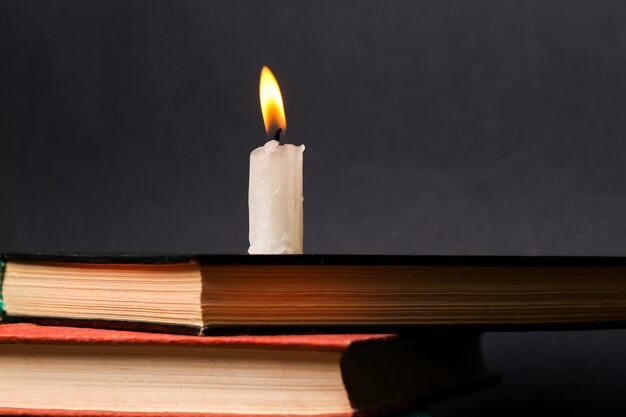 Vela en llamas en una pila de libros de fondo negro