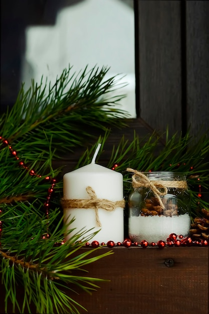 Vela en la mesa cerca del árbol de Navidad. Regalo de Navidad. Actitud festiva. Velas rojas y blancas. Decoración navideña.