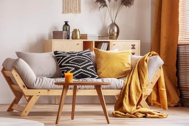 Vela naranja en una mesa baja de madera en el acogedor interior de la sala de estar