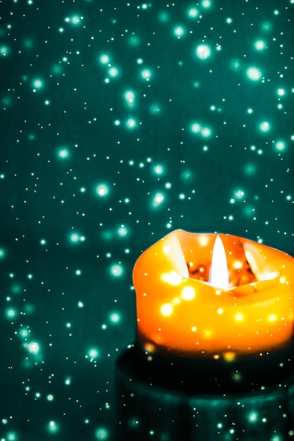 Foto vela navideña naranja sobre fondo de nieve verde brillante diseño de marca de lujo para halloween nochevieja y navidad