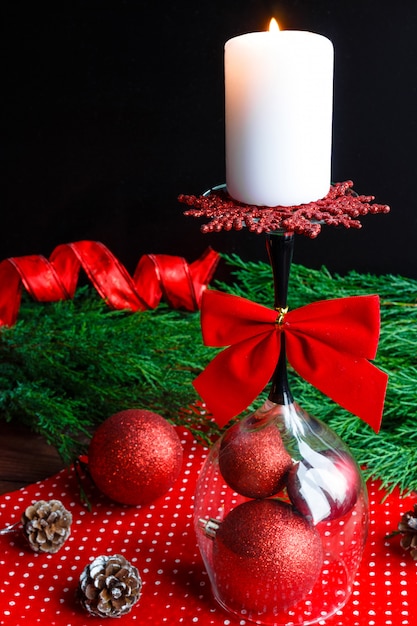 Vela navideña sobre un vidrio invertido, ramas de pino abeto y decoraciones navideñas desi