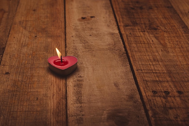 Vela perfumada em forma de coração acesa em uma mesa de madeira