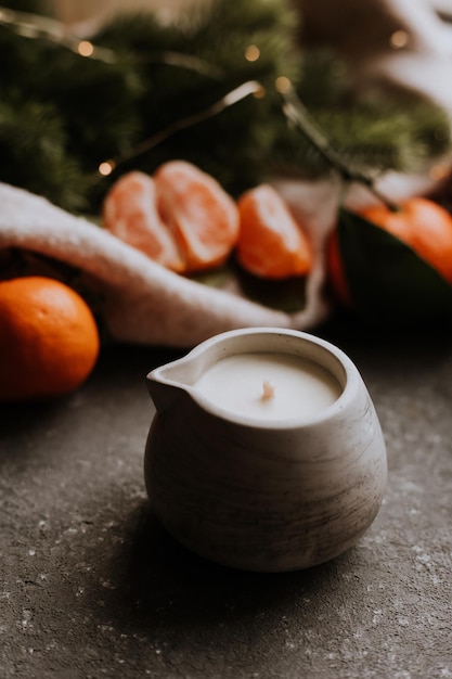 Vela perfumada hecha a mano sobre un fondo de hormigón gris junto a mandarinas Regalos para Navidad Año Nuevo39s comodidad en casa