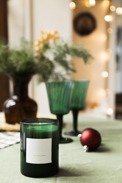 Vela perfumada en un vaso sobre una mesa con decoración navideña