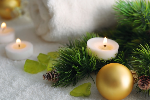 Vela en la rama de un árbol de pino y adornos navideños, primer plano