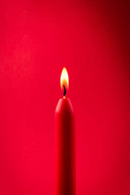Foto vela roja arde sobre fondo rojo.