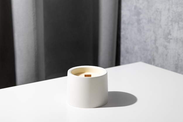 Vela de soja casera en cerámica ardiendo en un ambiente interior moderno gris y composición minimalista