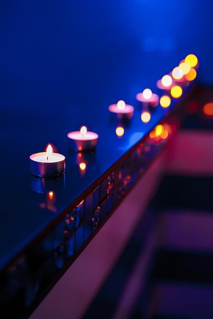 Vela de té y luces de velas desenfocadas sobre fondo azul.