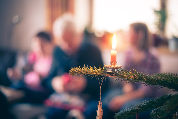 Vela en el tradicional árbol de Navidad decorado por la noche Gente en el fondo borroso