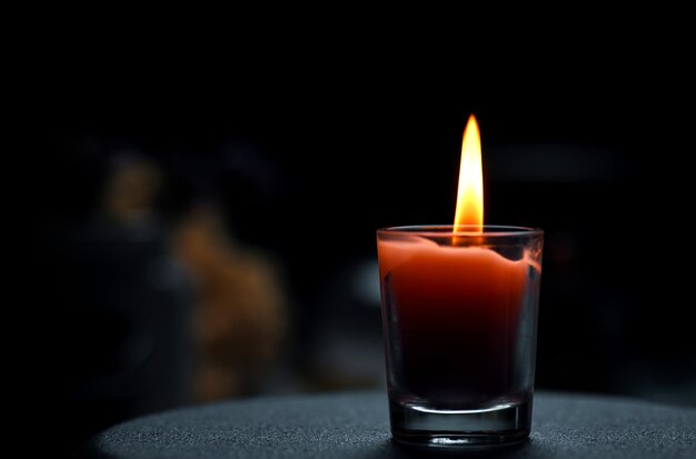 Una vela en un vaso con fondo negro.