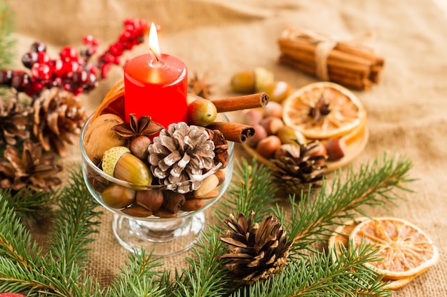 Vela vermelha de Natal na composição da decoração com cones, galhos, applecols, bolotas.