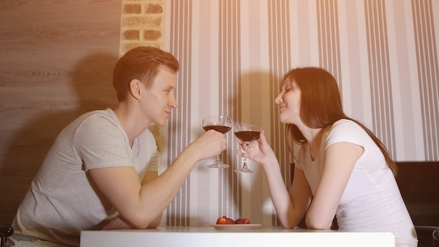 Velada romantica. Hombre y mujer en la mesa bebiendo vino, luz del sol