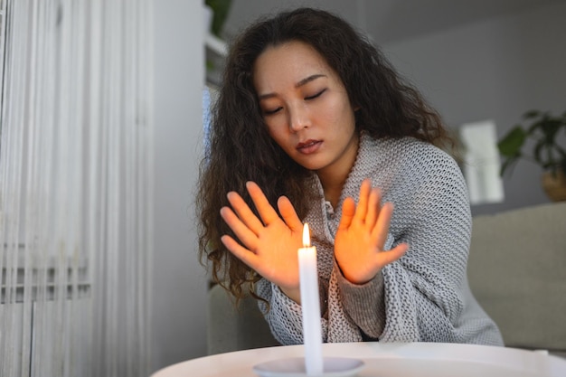 Velas acesas mulheres tentando aquecer as mãos em casa escura Desligamento do aquecimento e falta de energia elétrica queda de carga ou crise de energia