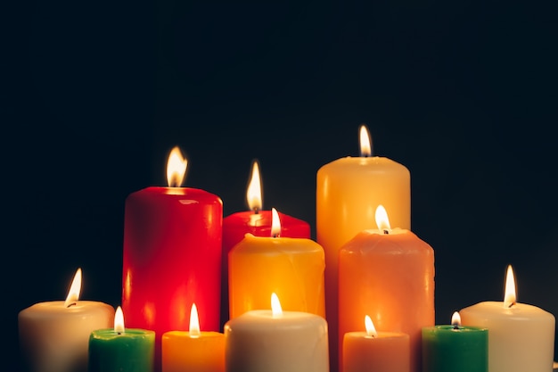 Velas acesas na escuridão sobre o preto.