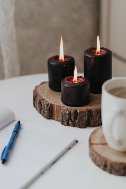 velas acesas um caderno de trabalho uma xícara de café bloco de notas uma caneta fogo vela