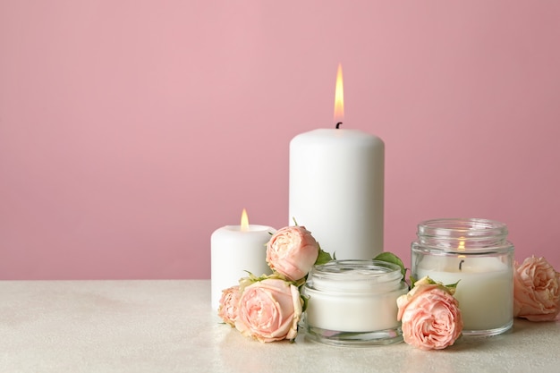 Velas aromáticas y rosas en el cuadro blanco contra el fondo de color rosa