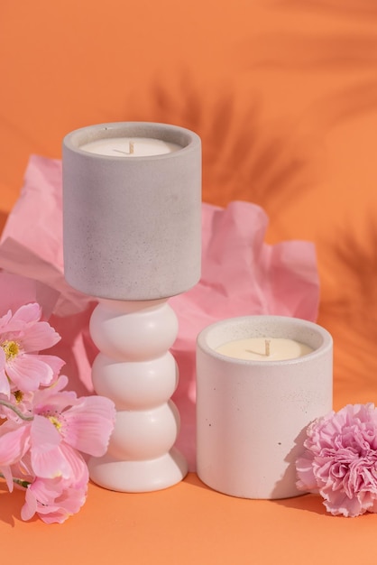 Foto velas aromáticas de soja premium en tarro de hormigón gris sobre fondo naranja con flor rosa y sombra