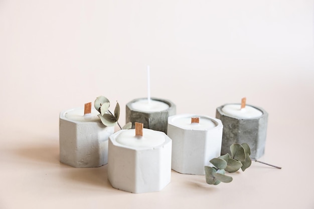 Velas artesanais de parafina e cera de soja em castiçal de gesso concreto com pavio de madeira e ervas secas isoladas em fundo bege pastel Copie o espaço