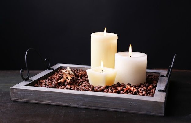 Velas en bandeja vintage con granos de café y especias en mesa de madera