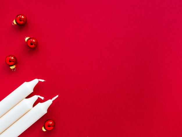 Velas brancas e bolas de Natal em um fundo de papel vermelho