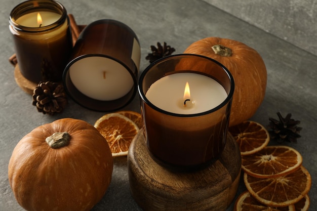 Velas, calabazas y naranjas sobre un fondo gris.