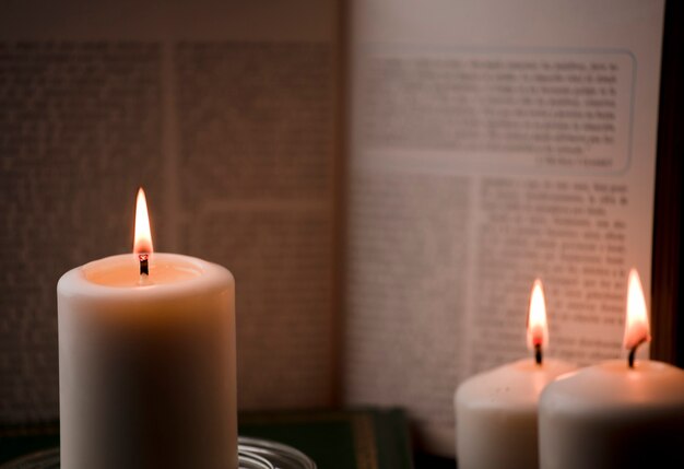 Velas com chama e livro de leitura na mesa com fundo preto