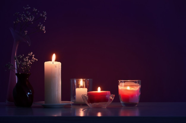 velas com flores na mesa de madeira branca sobre fundo roxo