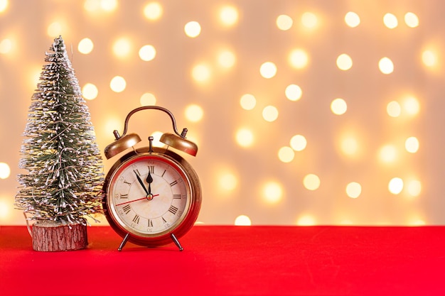 Velas de boneco de neve de trenó de relógio de árvore de Natal presentes em um fundo vermelho e um fundo de luzes