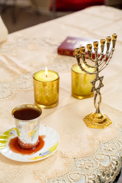 Foto velas de shabat, menorá e uma taça de vinho de kidush na mesa.