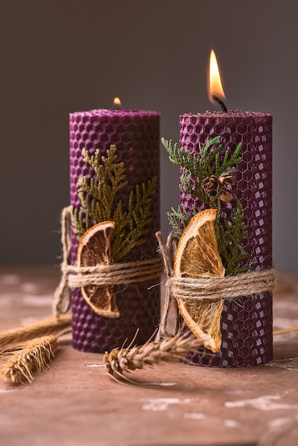 Velas decorativas de color púrpura hechas de cera de abejas con un aroma a miel para interiores y tradición.