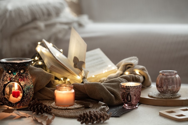 Velas em castiçais, livro, suéter, guirlanda. espaço da cópia do conceito de outono em casa.