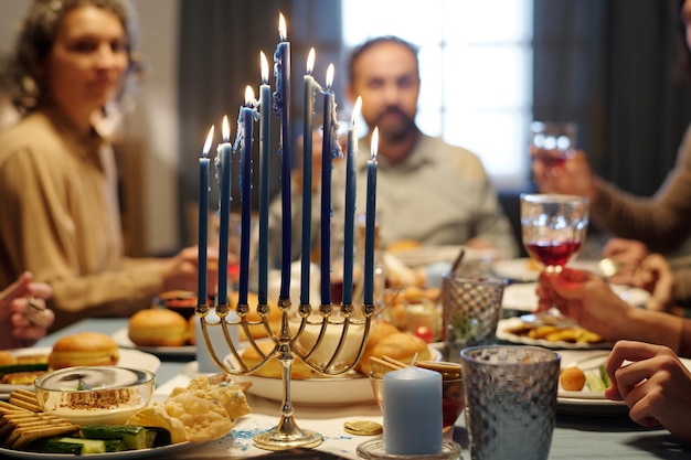 Velas encendidas en el candelabro de la menorá de pie en la mesa servida para la cena