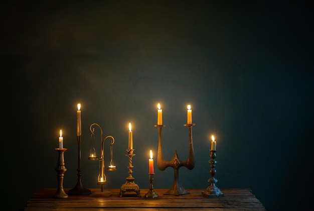 Velas encendidas en candelabros vintage sobre fondo oscuro