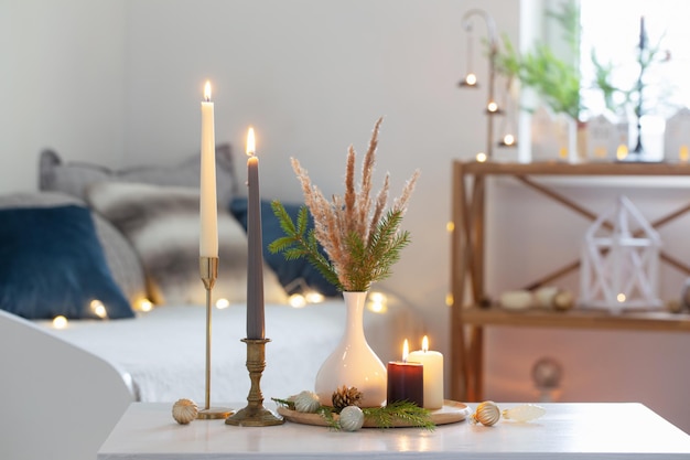 Velas encendidas con decoración navideña en un interior blanco y acogedor