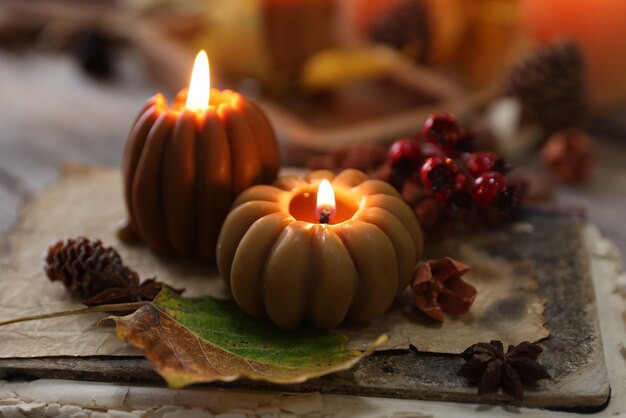 Velas encendidas en forma de calabazas libro antiguo y decoración de otoño en la mesa de primer plano