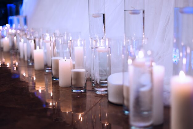 Velas encendidas frente a la mesa con mantel pequeñas velas en jarrones transparentes con agua