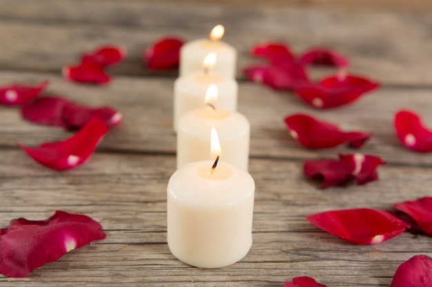 Velas encendidas rodeadas de aromáticos pétalos de rosa